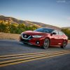 Red 2021 Nissan Maxima driving on highway with mountains and trees in the distance