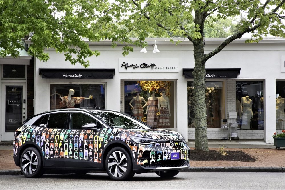 A Volkswagen ID.4, wrapped in an alice and olivia Pride Month design, is parked in front of the alice and olivia storefront