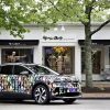 A Volkswagen ID.4, wrapped in an alice and olivia Pride Month design, is parked in front of the alice and olivia storefront