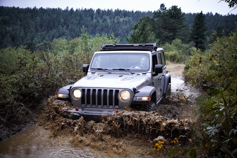 The 2021 Jeep Wrangler Rubicon with the Sunrider Flip Top for Hardtop driving through mud