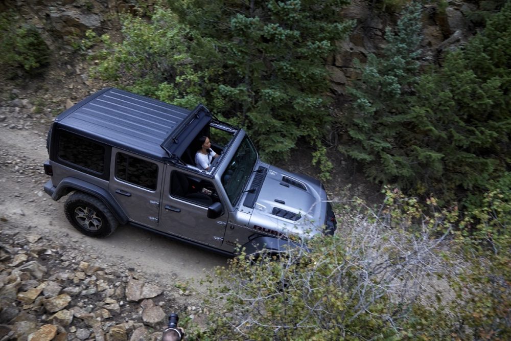 The 2021 Jeep Wrangler Rubicon with the Sunrider Flip Top for Hardtop driving on a dirt path