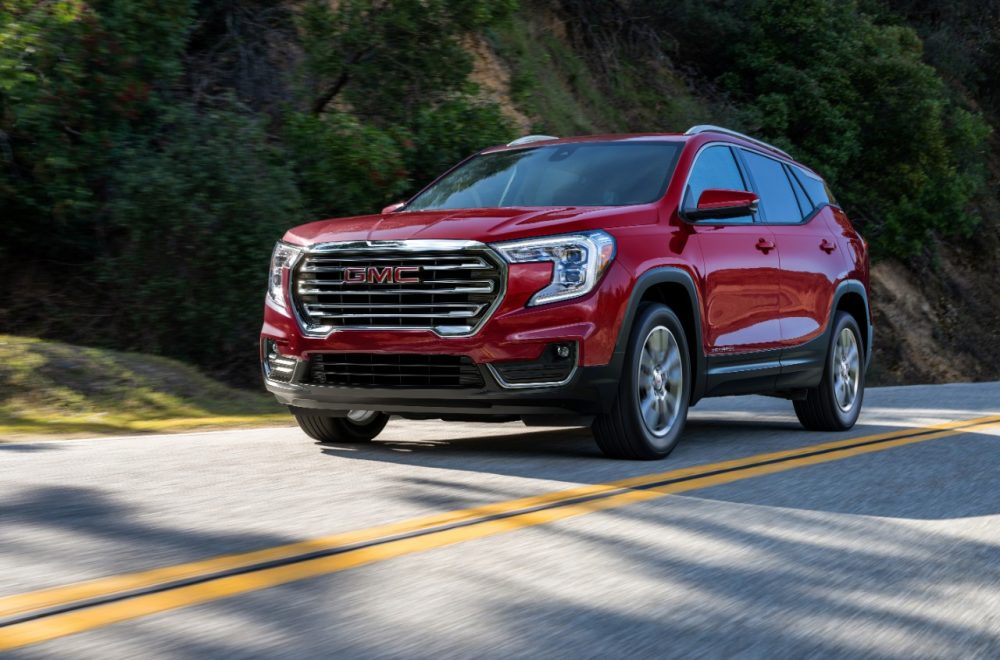 Red 2022 GMC Terrain SLT driving alongside a grassy hillside