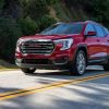 Red 2022 GMC Terrain SLT driving alongside a grassy hillside