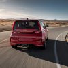 Exterior rear photo of a red 2022 Kia Soul driving around a curve on a deserted road