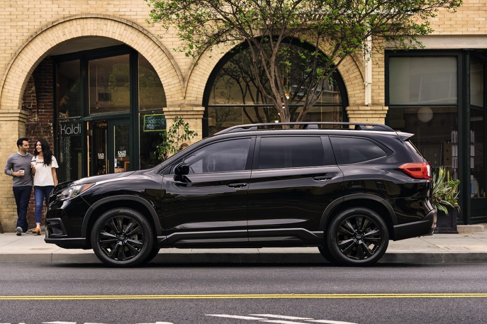 A black 2022 Subaru Ascent Onyx Edition parked in front of a city building while a couple walks by