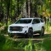 Front side view of GMC Acadia AT4 parked in wooded clearing