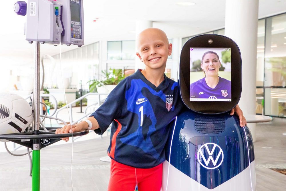 Cancer patient and soccer player Luna Perrone poses with the CHAMP robot with Alex Morgan's face displayed on its screen
