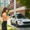 Woman hailing an autonomous Ford Escape through Lyft