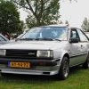 A light gray/silver 1982 Nissan Sunny (also called the Sentra) parked on grass at an auto show in Japan