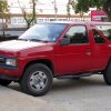 A red 1989 Nissan Pathfinder parked at a convenience store