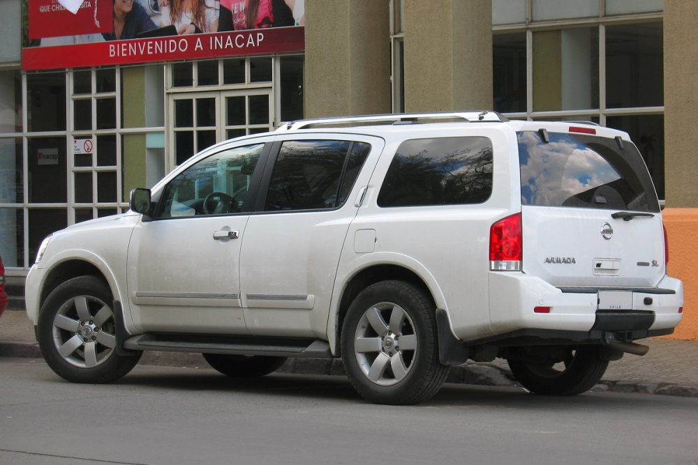 Rear side view of a white 2011 Nissan Armada parked in front of a city building