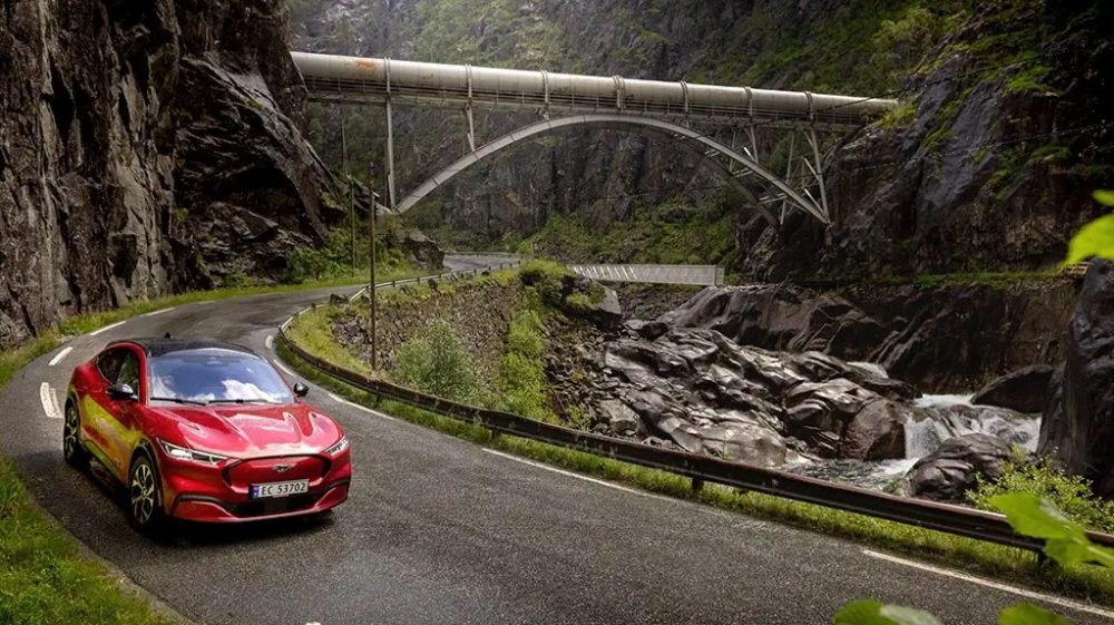 2021 Ford Mustang Mach-E turning a corner by a bridge in Norway