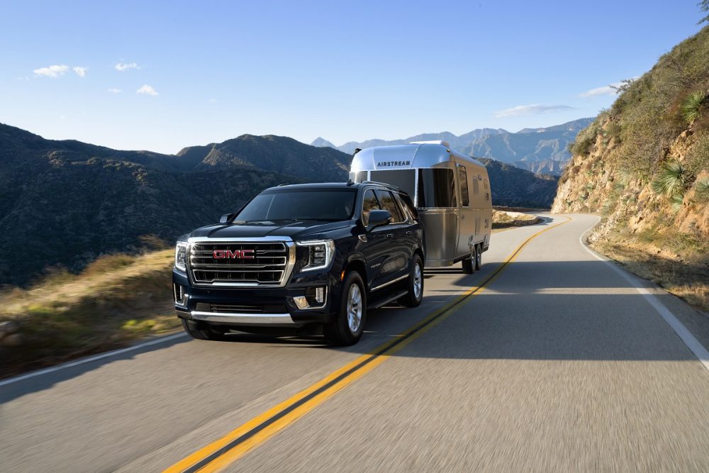 Front side view of 2021 GMC Yukon towing a trailer down the road