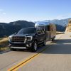 Front side view of 2021 GMC Yukon towing a trailer down the road