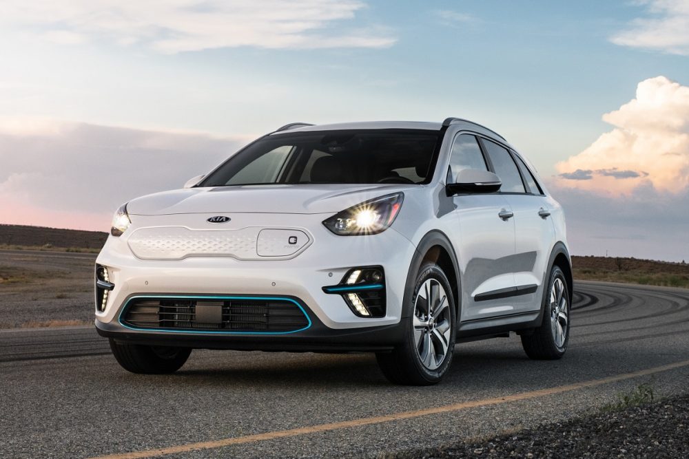 A white 2021 Kia Niro EV parked on a deserted highway at sunset