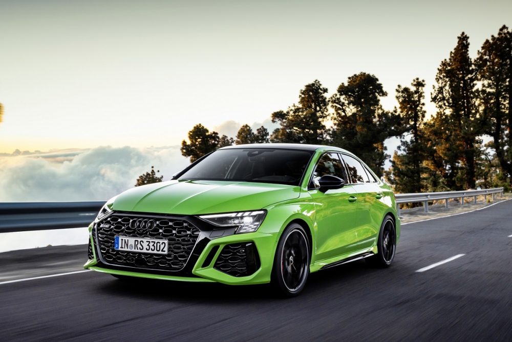 Front view of a bright green 2022 Audi RS 3 driving on a highway