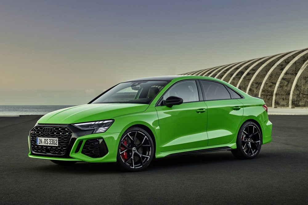 Front side view of the 2022 Audi RS 3, in bright green, parked on concrete in front of water