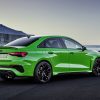 Rear side view of the 2022 Audi RS 3, in bright green, parked on concrete in front of water