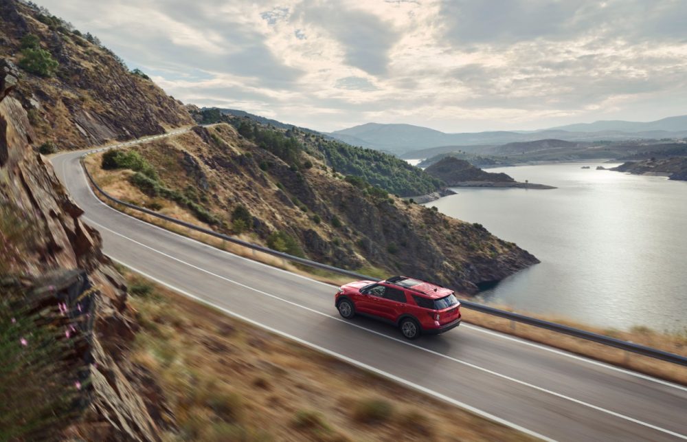 2022 Ford Explorer ST-Line racing along a mountain road overlooking a lake