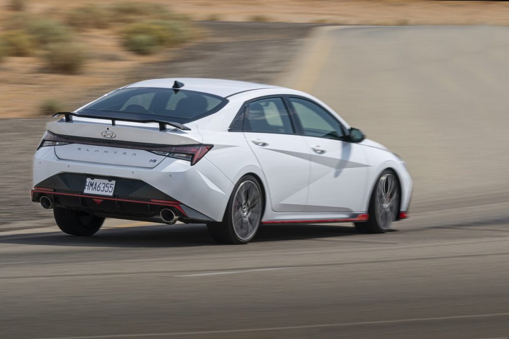 Rear side view of white 2022 Hyundai Elantra N cornering on a track