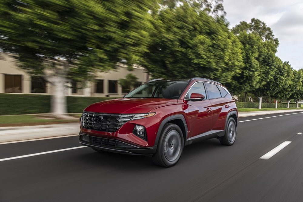 Front side view of red 2022 Hyundai Tucson driving down street