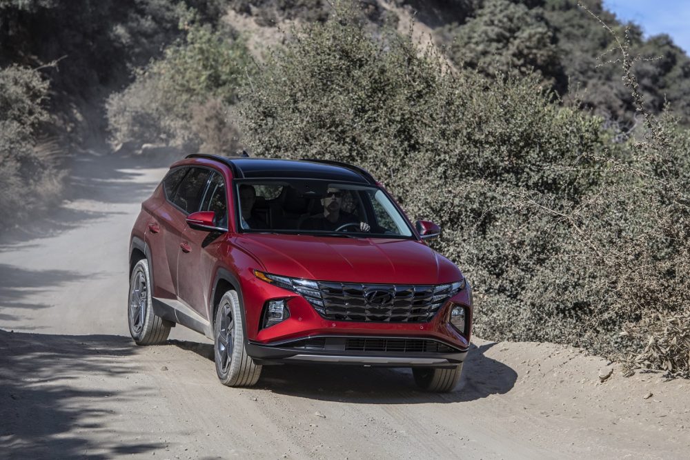 Front side view of red 2022 Hyundai Tucson on dusty off-road trail