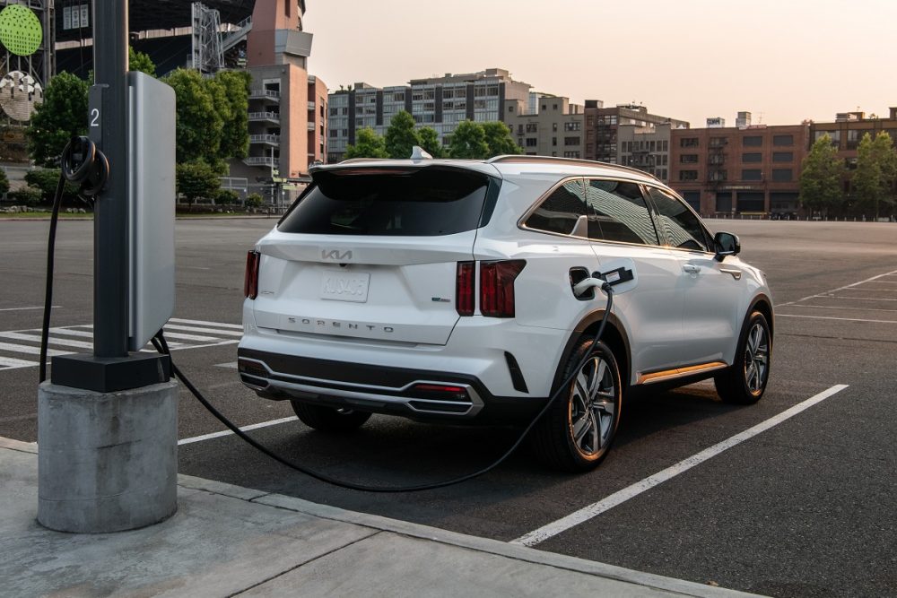 Exterior rear view of the 2022 Kia Sorento PHEV at sunset while it's getting charged