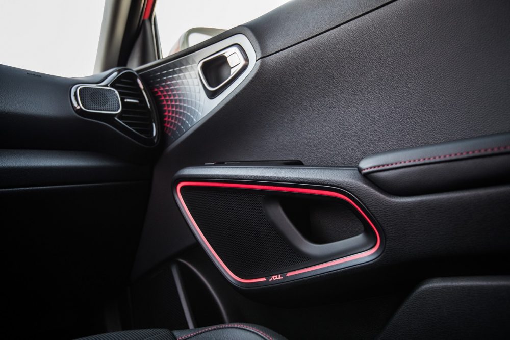 Interior photo of front passenger's side in the 2022 Kia Soul, focusing on a lit up door handle and speaker