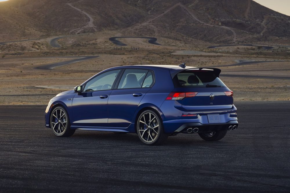 Rear view of a blue 2022 Volkswagen Golf R parked on pavement with mountains behind