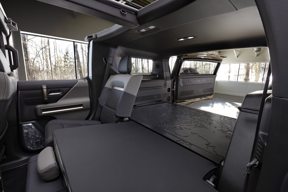 Interior view of the 2024 GMC Hummer EV SUV with its rear seat folded down partially to expose the cargo area