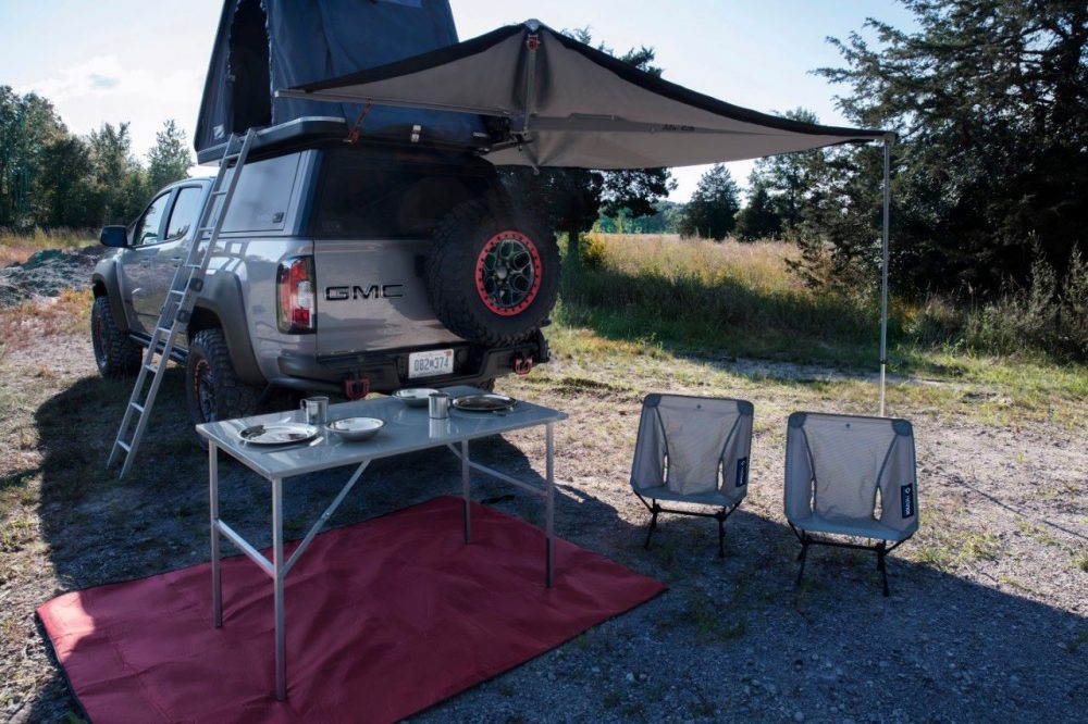 roof-mounted tent of GMC Canyon AT OVRLANDX Concept Truck with table and chairs set out