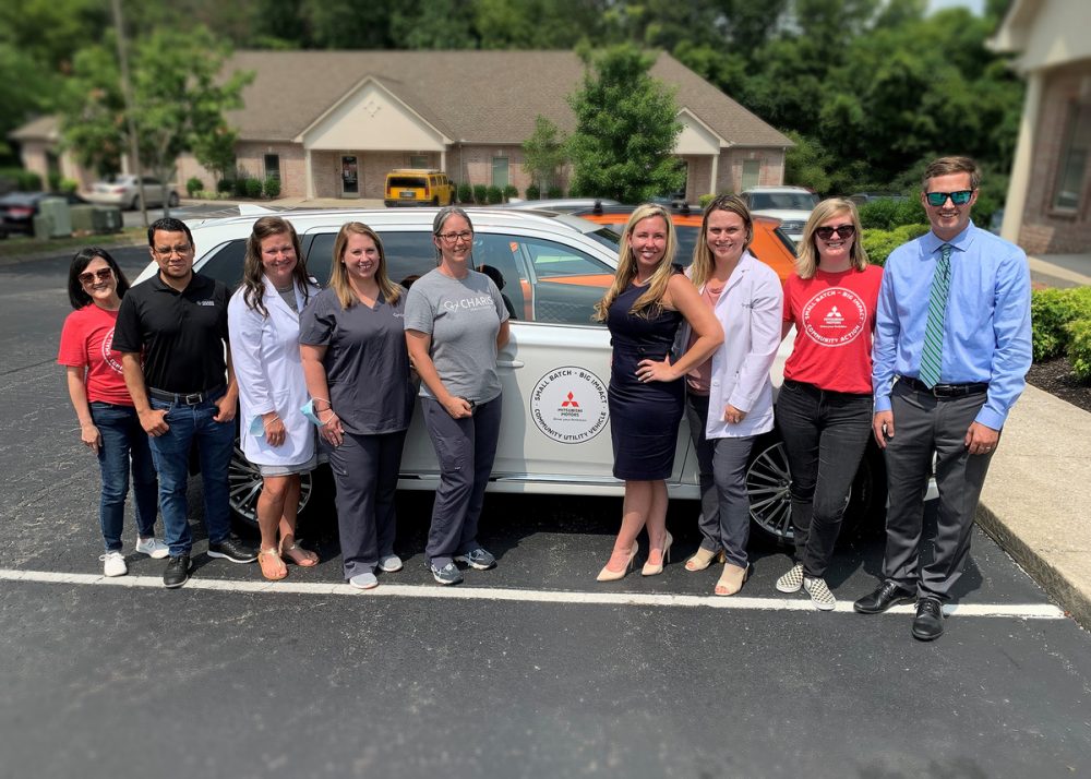 People standing in front of the Outlander PHEV donated to Charis Health Center