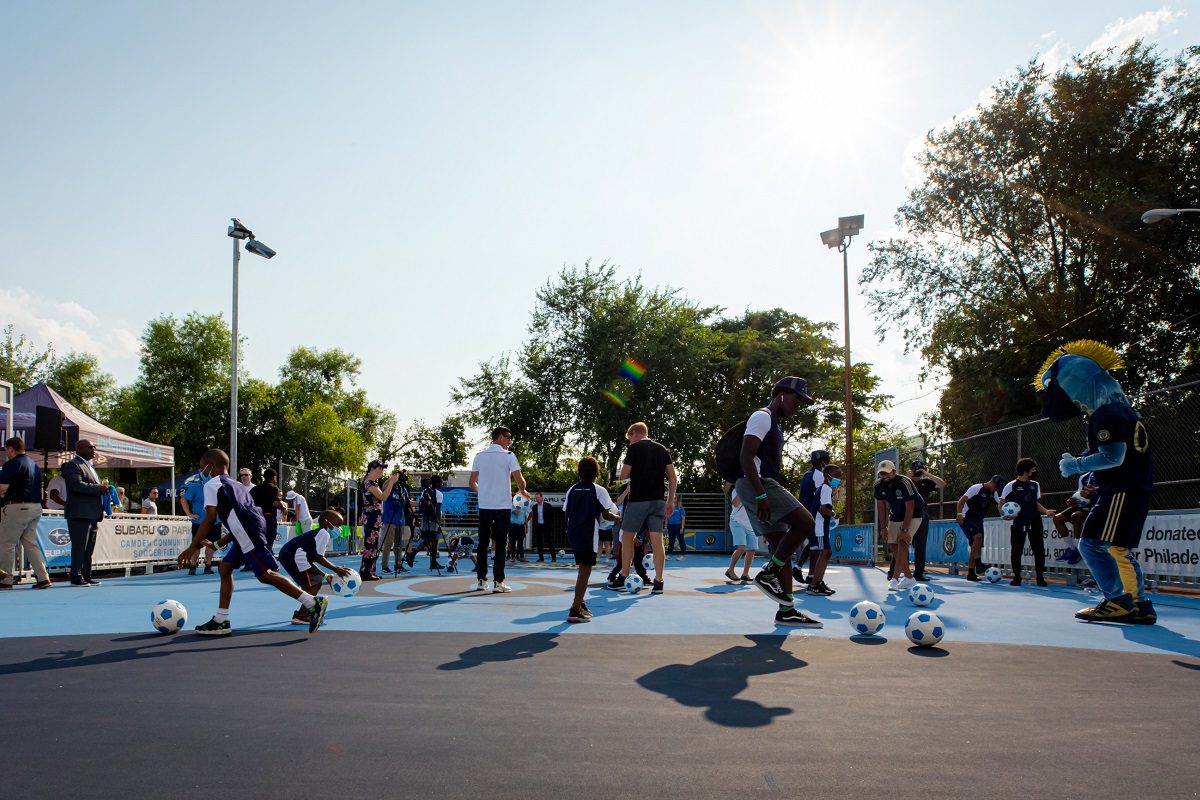 Kids and Philadelphia Union players kick soccer balls on the Subaru Park Camden Mini-Pitch