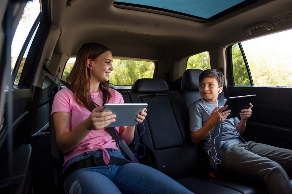 Two children in the backseat of a Volkswagen using tablets