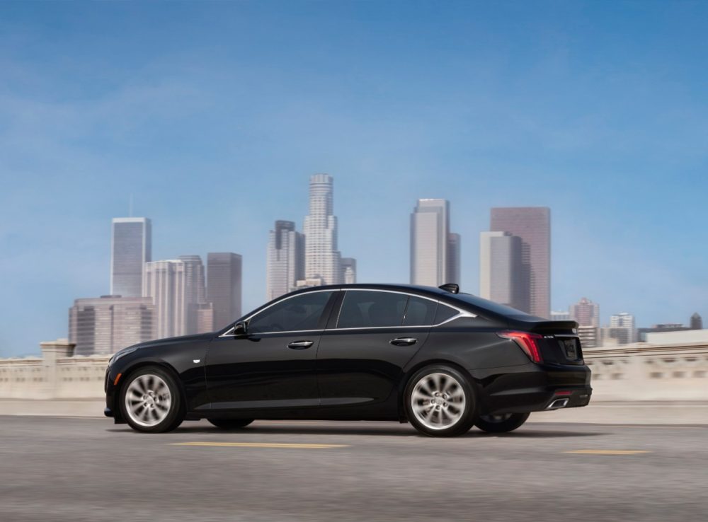 The 2021 Cadillac CT5 driving on a highway with a city skyline in the background