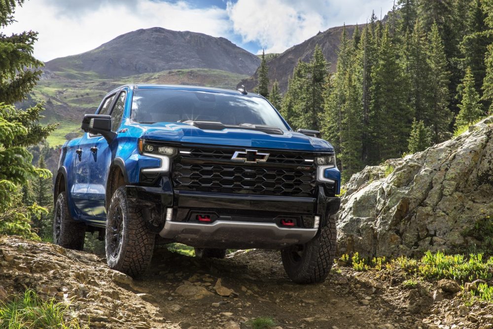 Front view of 2022 Chevrolet Silverado 1500 ZR2 driving on hilly dirt road with mountains in background