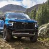 Front view of 2022 Chevrolet Silverado 1500 ZR2 driving on hilly dirt road with mountains in background