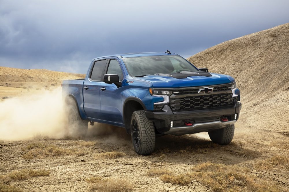 Front side view of 2022 Chevrolet Silverado 1500 ZR2 driving across rugged ground while kicking up dust cloud