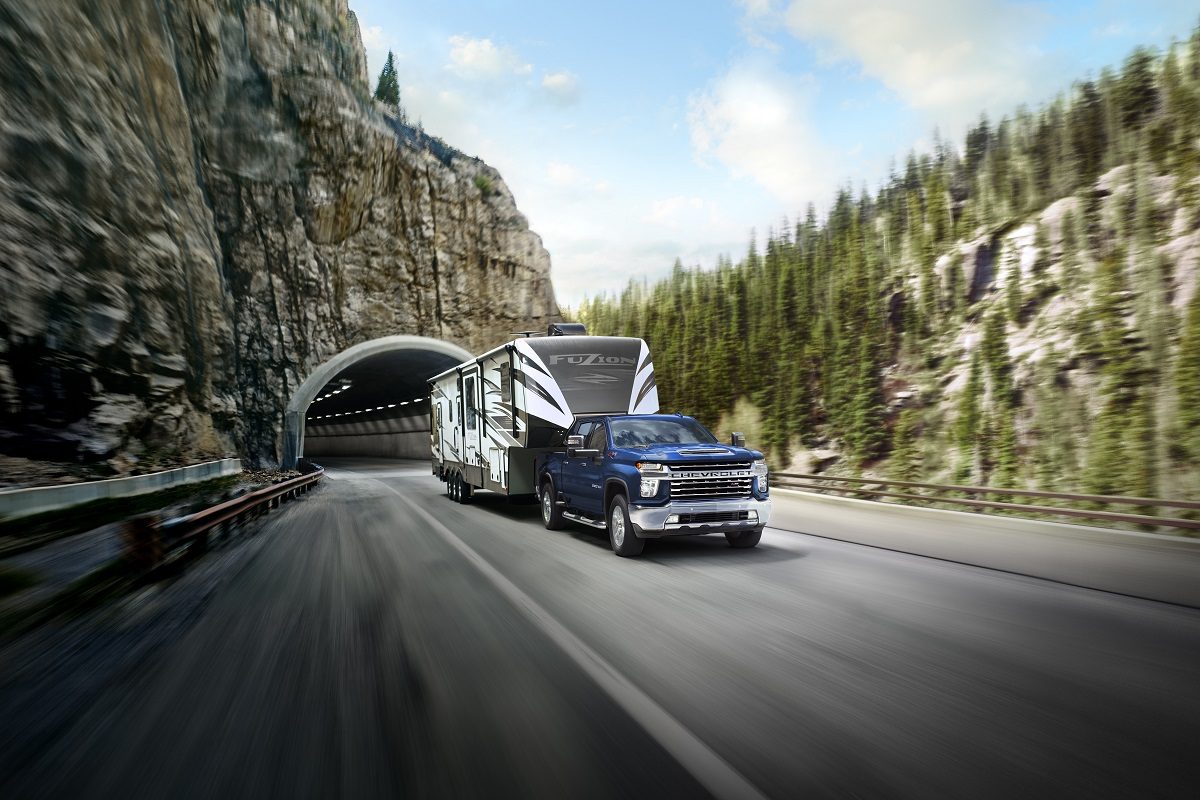 A blue 2022 Chevrolet Silverado 2500HD towing a trailer drives out of a tunnel