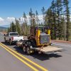 A white 2022 Chevrolet Silverado 2500HD tows work equipment on a highway