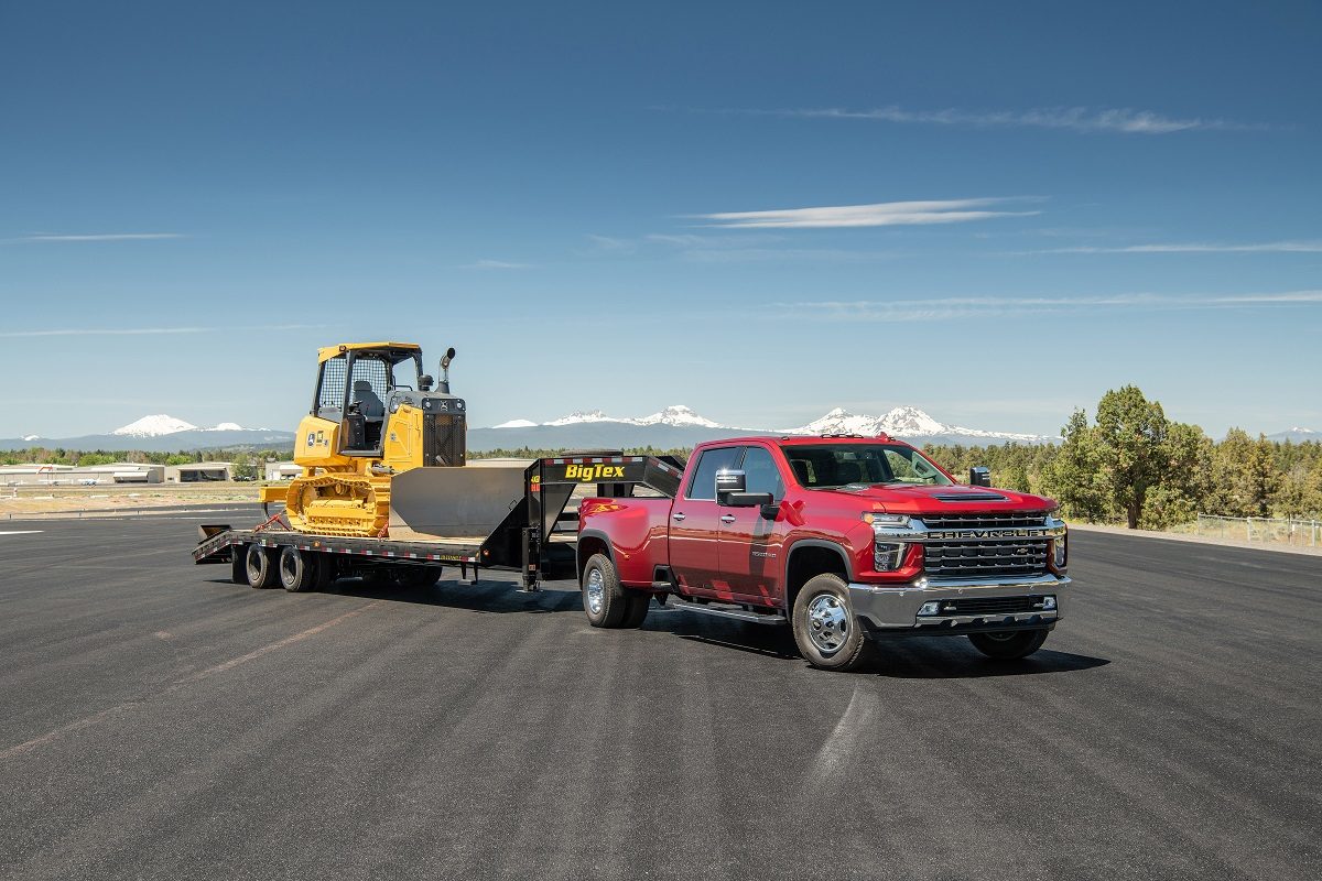 A red 2022 Chevrolet Silverado 3500HD tows work equipment