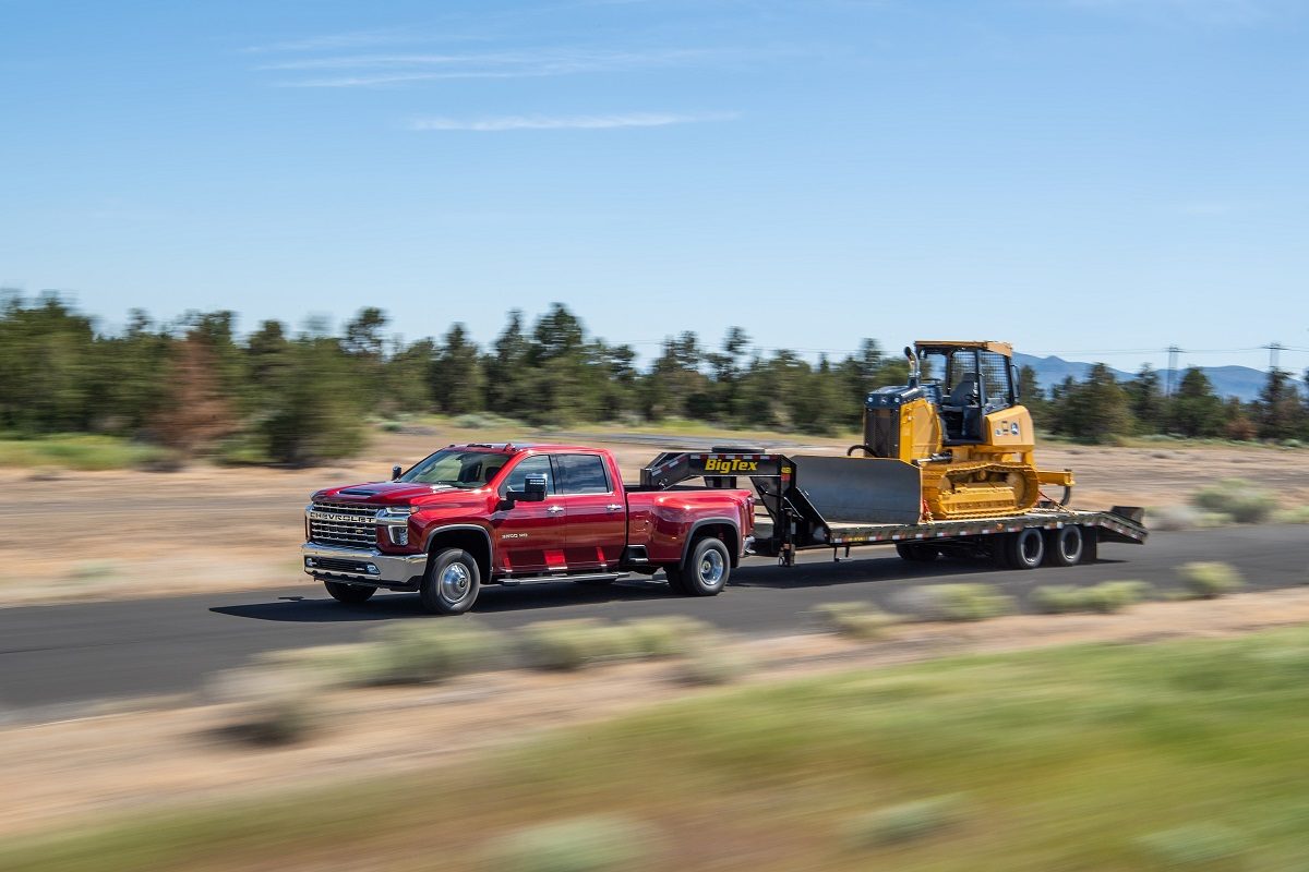 A red 2022 Chevrolet Silverado 3500HD tows work equipment