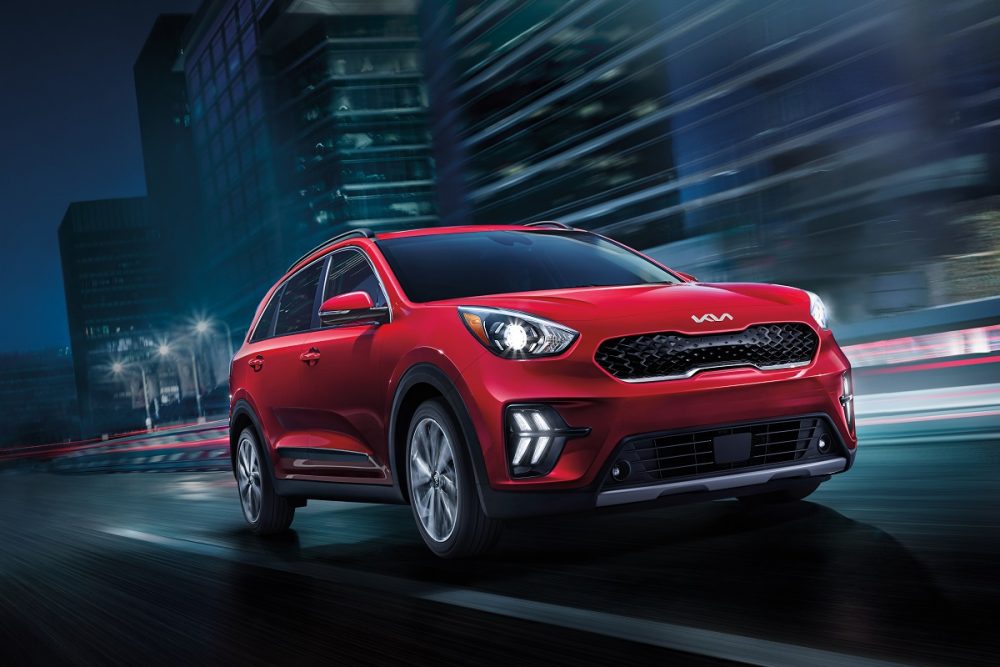 A red 2022 Kia Niro drives fast at night on a city street