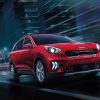 A red 2022 Kia Niro drives fast at night on a city street