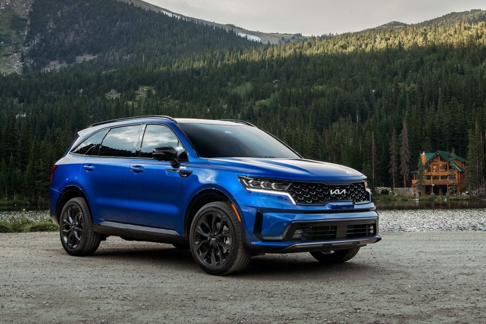 Front side view of a blue 2022 Kia Sorento parked in front of a lake