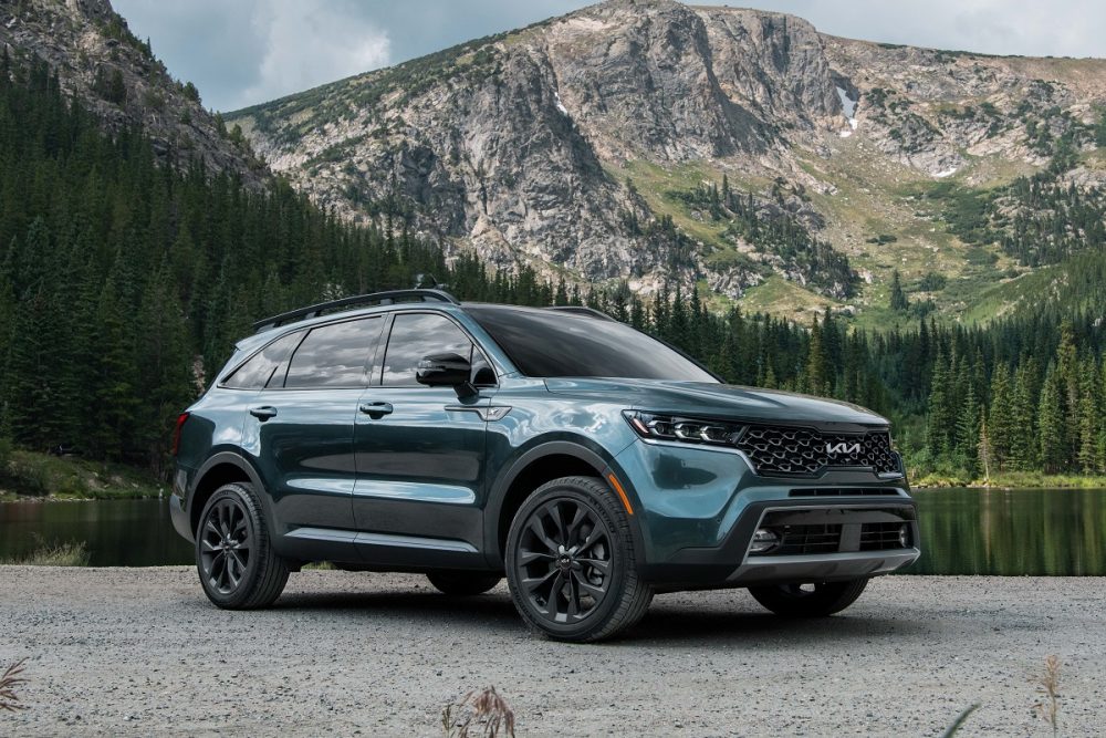 Front side view of a green 2022 Kia Sorento parked in front of a lake