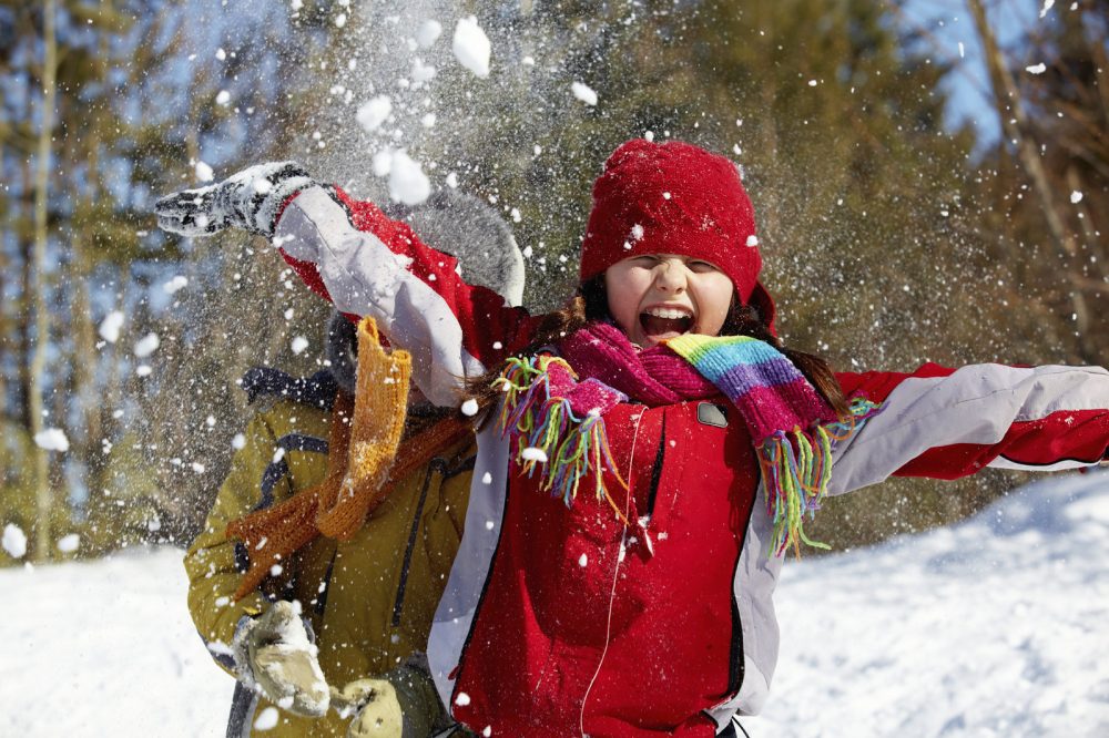 child in winter clothing playing in the snow