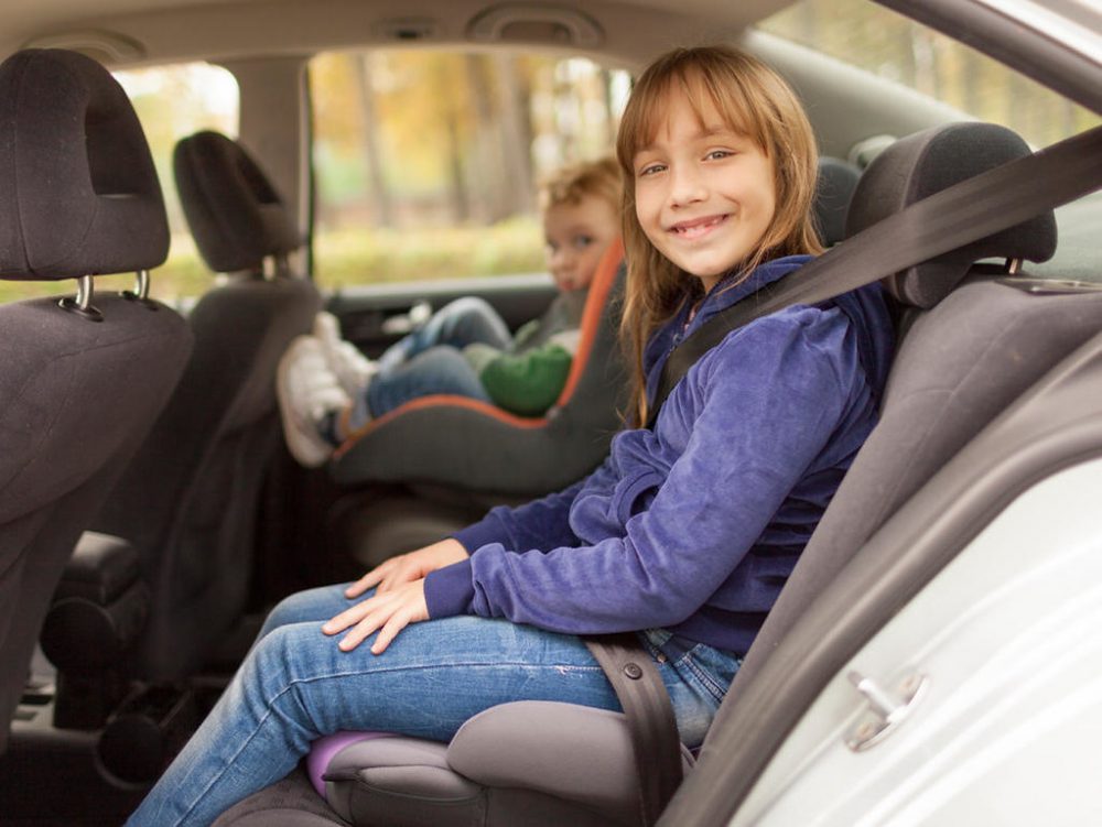 child sitting in a high-back booster seat inside a car