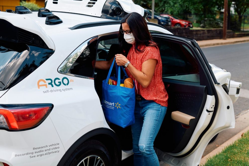 A customer retrieves a grocery bag from the backseat of a Ford Escape Hybrid