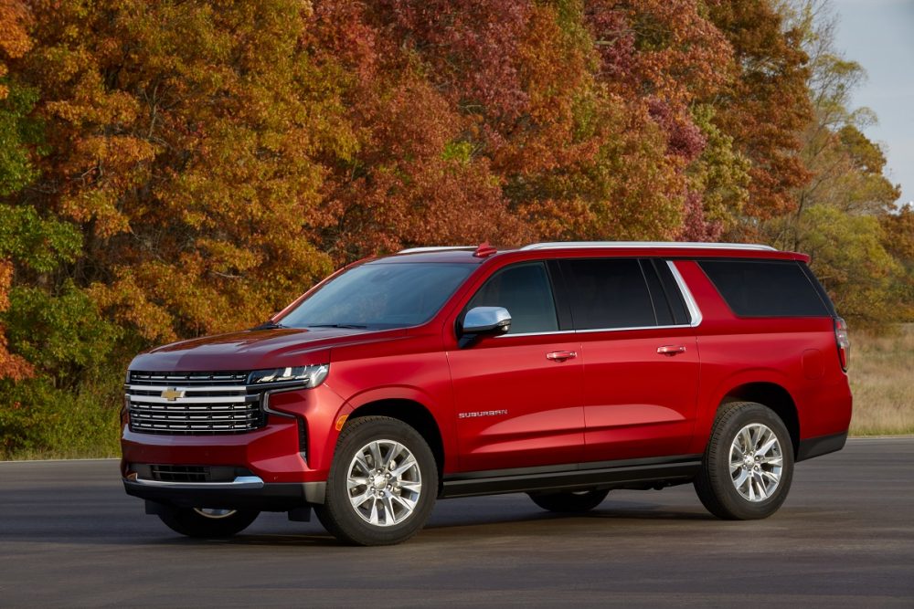 Front side view of parked 2022 Chevrolet Suburban with trees in background